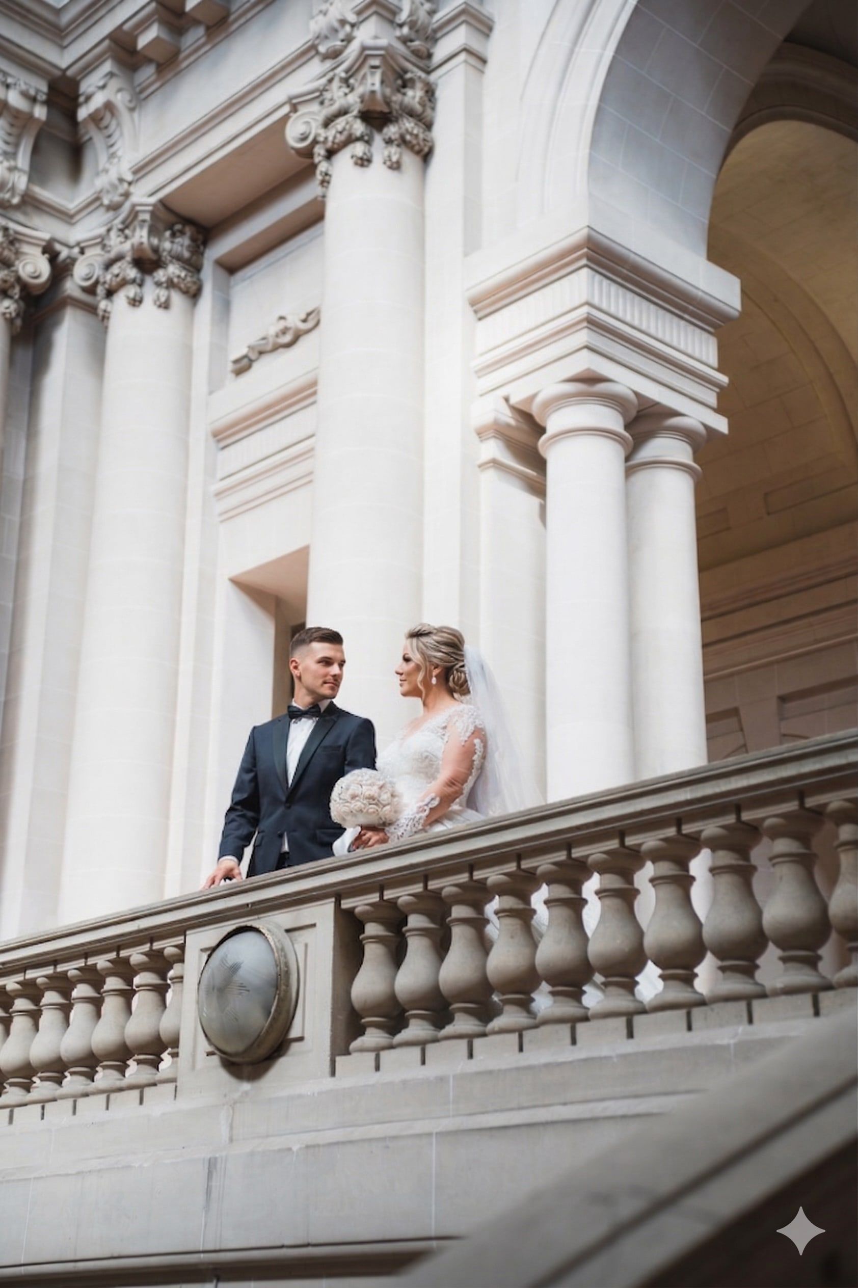 Les mariés au balcon d’une façade classique à colonnes.